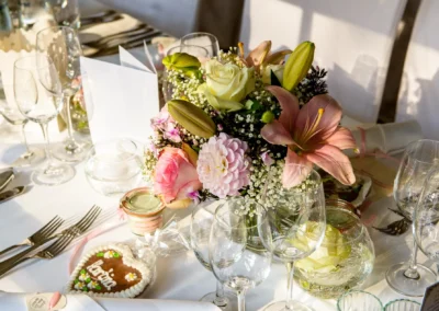 Elegante Tischdeko bei Hochzeit im Hotel Aiterbach am Chiemsee mit Blumenarrangement und Herz-Lebkuchen.
