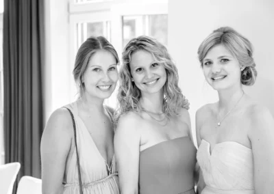 Drei lachende Frauen bei Hochzeit im Hotel Aiterbach am Chiemsee, elegante Feier und festliche Kleidung.