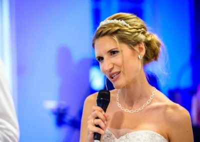 Braut mit Mikrofon bei Hochzeit im Hotel Aiterbach am Chiemsee, festliche Feier mit eleganter Stimmung.