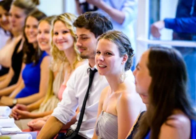 Hochzeit im Hotel Aiterbach am Chiemsee, Gaeste lachen waehrend Feierlichkeiten. Elegante Hochzeitsreportage.