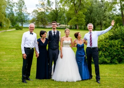 Hochzeitspaar mit Familie im Garten des Hotel Aiterbach am Chiemsee, festliche Stimmung und Naturkulisse.