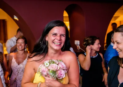 Lachende Gaeste bei einer abendlichen Hochzeitsfeier in Muenchen mit Blumenstrauss.