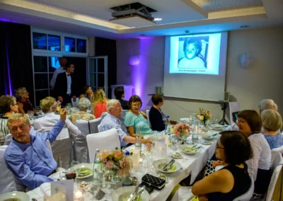 Hochzeitsgesellschaft bei einer Diashow im Hotel Aiterbach, Chiemsee. Feiern und Erinnerungen teilen.