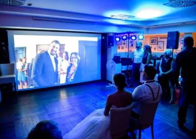 Hochzeitsfeier am Abend in Muenchen mit Videoprojektion und Gaesten in festlicher Stimmung.