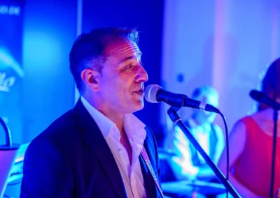 Musiker singt bei Hochzeit im Hotel Aiterbach am Chiemsee, stimmungsvolle Beleuchtung im Hintergrund.