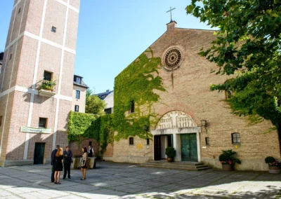Hochzeitsfeier in Sendling, Brautpaar und Gaeste vor Kirche mit Efeu an Fassade, Hochzeitsreportage in Muenchen.
