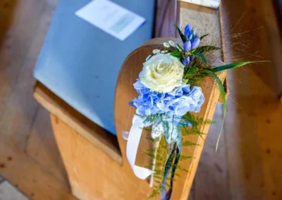 Kirchensitzbank mit Blumenarrangement bei einer Hochzeit in Sendling, Munchen. Hochzeitsreportage in Oberbayern.