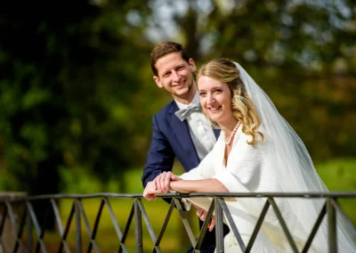 Brautpaarfotos in Bernried am Starnberger See: Lächelndes Paar auf Brücke bei Hochzeit. Hochzeitsfotografie in Bayern.