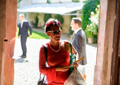 Frau in rotem Kleid bei kirchlicher Trauung in Schloss Blutenburg, Oberbayern; Hochzeitsreportage.