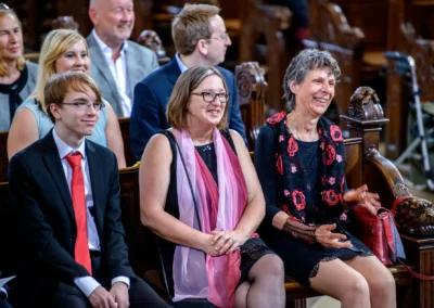 Gäste lächeln während der kirchlichen Trauung bei einer Hochzeit in der Lukaskirche, aufgenommen in München-Lehel.
