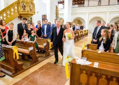 Braut wird bei kirchlicher Trauung in der Stadtpfarrkirche Maria Himmelfahrt in Oberbayern zum Altar gefuehrt.