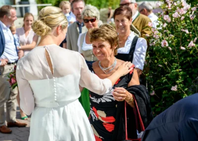 Braut bei der Begruessung der Gaeste bei der Hochzeit im Rathaus Tegernsee. Hochzeitsreportage in Bayern.