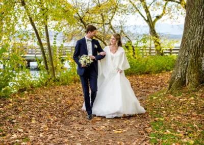 Brautpaar laechelnd im herbstlichen Park, Hochzeitsfotografie in Bernried, natuerlich am Starnberger See.
