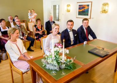 Brautpaar im Standesamt am Tegernsee bei der Hochzeitsreportage, umgeben von Freunden und Familie.