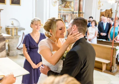 Brautpaar in St. Michael Kirche während Trauung in München, glücklicher Moment umgeben von Gästen, Hochzeitsreportage.