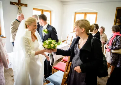 Braut in weissem Kleid bei standesamtlicher Trauung in Dietramszell, Oberbayern, gratuliert Gaesten.