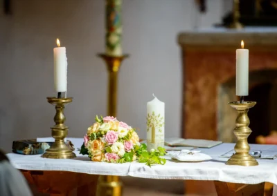 Kerzen und Blumenstrauss auf Altartisch bei kirchlicher Trauung in Schloss Blutenburg, Oberbayern. Hochzeitsreportage.