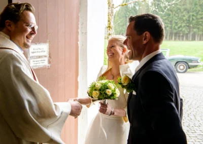 Brautpaar und Priester bei kirchlicher Trauung in Dietramszell, suedoestlich von Muenchen. Hochzeit Reportage.