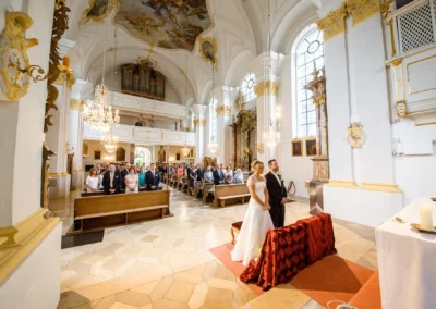 Brautpaar bei kirchlicher Trauung in St. Michael, Muenchen. Hochzeitsreportage mit Gaesten in festlicher Kirche.