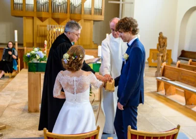 Zeremonie in Kirche in Sendling, Brautpaar mit Priester und Pfarrer. Hochzeitsfotograf aus Muenchen erstellt Reportage.