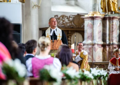 Pfarrer bei kirchlicher Trauung in Königsdorf mit Gästen, Blumen und Altarkerzen, Hochzeitsreportage südlich von München.