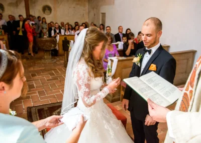Kirchliche Trauung in Schloss Blutenburg, München: Brautpaar tauscht Ringe vor Gästen. Hochzeitsreportage Oberbayern.