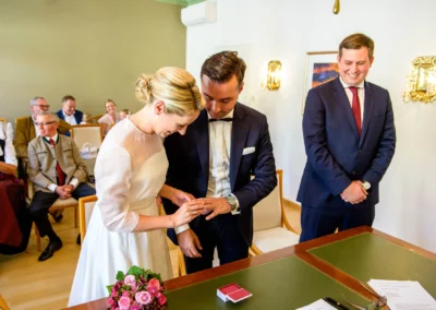 Brautpaar tauscht Ringe vor Gästen im Rathaus Tegernsee. Hochzeitsreportage zeigt emotionale Momente der Trauung.