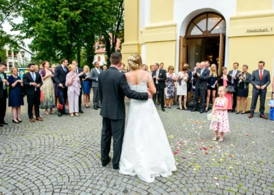 Brautpaar und Gaeste bei kirchlicher Trauung in St. Michael, Perlach. Hochzeitsfoto mit Blumenstreuende Kinder.