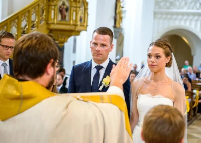 Priester segnet Brautpaar bei kirchlicher Trauung in Stadtpfarrkirche Maria Himmelfahrt, Bad Toelz. Hochzeitsfotografien.