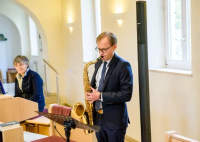 Musiker spielt Saxophon bei einer kirchlichen Trauung in Bernried. Hochzeitsfotografie in elegantem Ambiente.
