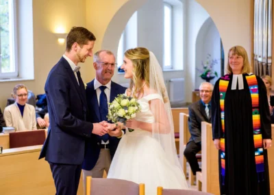 Brautpaar tauscht Ringe waehrend kirchlicher Trauung in Bernried. Hochzeitsreportage von Hochzeitsfotograf.
