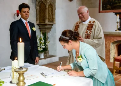 Braut unterschreibt bei kirchlicher Trauung in Schloss Blutenburg, Obermenzing. Hochzeitsreportage aus Oberbayern.