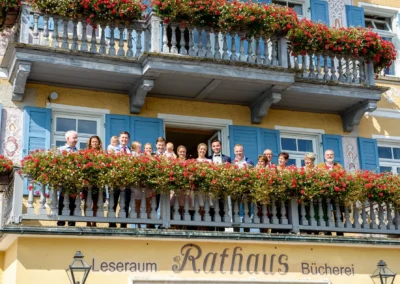 Gruppenszene bei Rathaus Tegernsee, Hochzeitsfoto mit Blumenbalkon in Bayern.