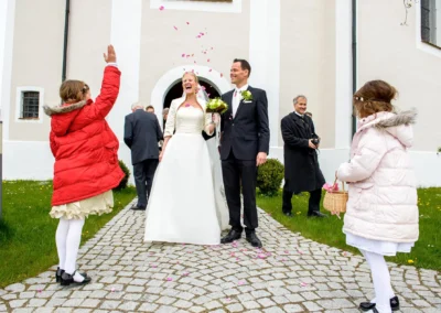 Brautpaar und Kinder vor der Kirche St. Leonhard bei Hochzeitsreportage in Dietramszell, Oberbayern.