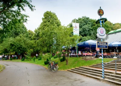 Hochzeitsfotografie im Wirtshaus am Rosengarten, München. Gäste genießen die Feier im grünen Biergarten.