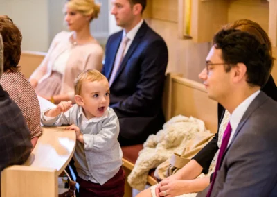 Kind bei Hochzeit in Kirche, umgeben von sitzenden Erwachsenen, gefangen von Hochzeitsfotograf in Bernried.