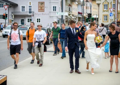 Brautpaar in Bad Toelz spaziert nach Hochzeit mit Hochzeitsgesellschaft. Hochzeitsfotografie in Oberbayern.