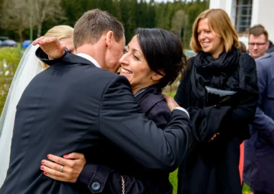 Brautpaar und Gaeste bei herzlicher Umarmung nach kirchlicher Trauung in St. Leonhard, Oberbayern, Hochzeit Reportage.