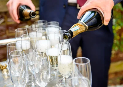 Hochzeitsfoto bei Rathaus Tegernsee: Sekt wird in Gläser für Hochzeitsfeier eingeschenkt. Elegante Hochzeitsreportage.