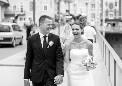 Brautpaar lacht Hand in Hand bei ihrer Hochzeit in Bad Toelz, aufgenommen von einem Hochzeitsfotografen.