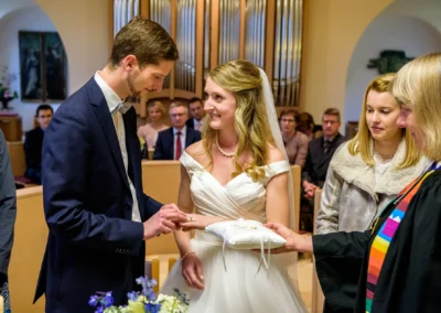 Brautpaar tauscht Ringe bei einer Hochzeit in Bernried, Brautstrauss im Vordergrund, emotionale Hochzeitsfotografie.