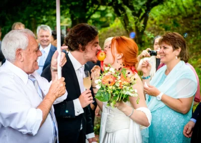 Brautpaar bei Hochzeitsfeier im Westpark mit Blumenstrauss und Apfel. Hochzeitsreportage in Sendling-Westpark.