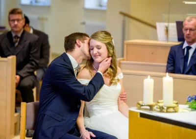 Brautpaar bei emotionaler Hochzeitszeremonie in Bernried, Hochzeitsfotografie mit Kerzen und Gaesten im Hintergrund.