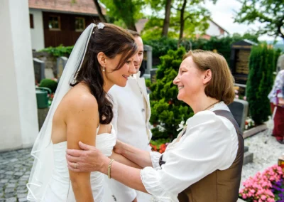 Braut bei kirchlicher Trauung in Königsdorf, lachen mit Hochzeitsgästen, festgehalten von Fotograf südlich von München.