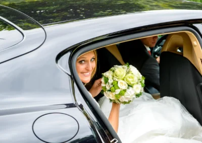 Braut in Hochzeitskleid mit Blumenstrauss im Auto bei kirchlicher Trauung in St. Michael, Pfanzeltplatz.