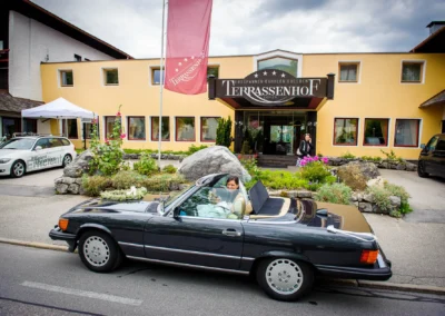 Braut im Cabrio vor Terrassenhof, Hochzeitsfeier in Bad Wiessee. Elegante Ankunft bei der Hochzeit südlich von Muenchen.
