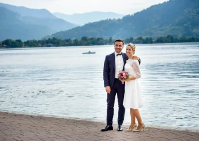 Brautpaar am Tegernsee mit Bergen im Hintergrund, Hochzeitsfotografie eingefangen vom Hochzeitsfotografen.