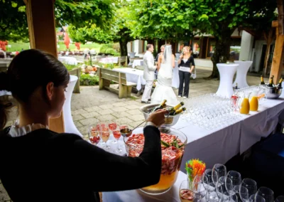 Hochzeitsfeier in Bad Wiessee, Bedienung serviert Sektempfang im Freien. Hochzeit bei Terrassenhof am Tegernsee.