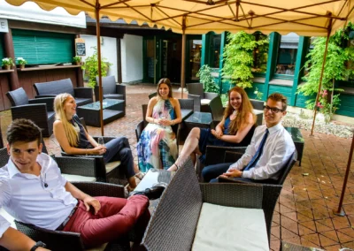 Gäste bei einer Hochzeit entspannen in einem Gartenrestaurant in München, Hochzeitsfoto mit fröhlicher Atmosphäre.
