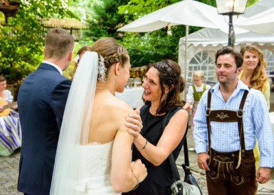 Braut im Gespraech mit Gaesten bei der Hochzeitsfeier im Hotel Kolbergarten, Bayern. Hochzeit im Freien.